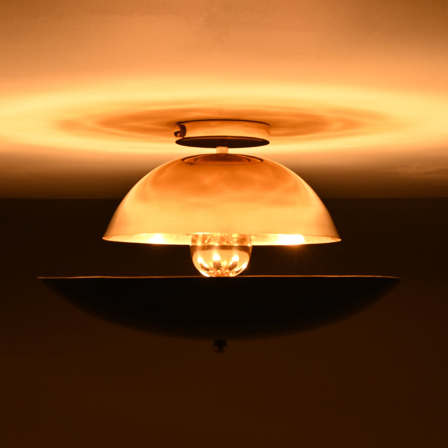 Front view of mixed-finish brass flushmount light with polished brass dome and blackened lower bowl, creating warm indirect illumination.