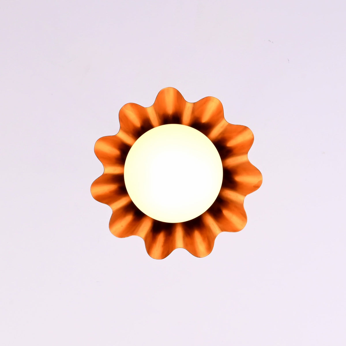 Bottom view of modern brass fluted disc pendant light with glowing glass globe and warm ambient illumination.