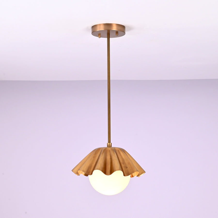 Minimalist brass fluted pendant light hanging straight with sculpted shade and glowing globe.