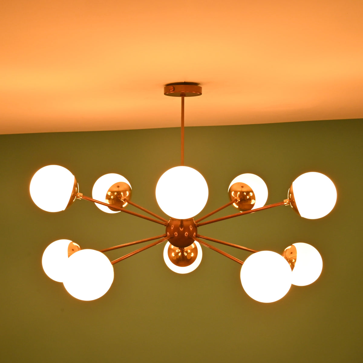 Bottom view of a handcrafted brass globe chandelier showing central hub detailing and evenly spaced light arms.