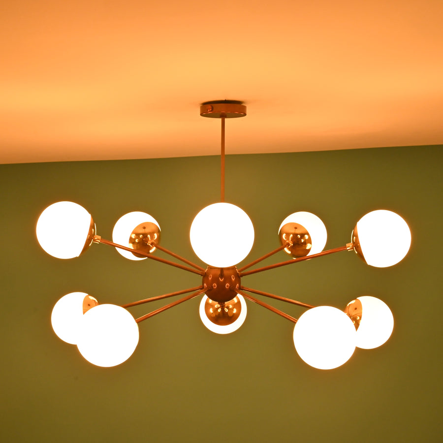 Front elevation of a 10 light brass globe chandelier featuring a central sphere and balanced mid century modern design.
