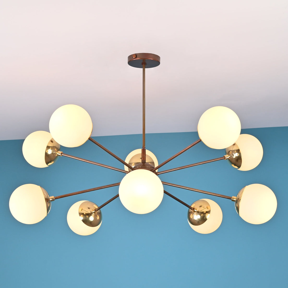 Symmetrical modern brass chandelier with opal globe shades arranged in a sculptural radial pattern.