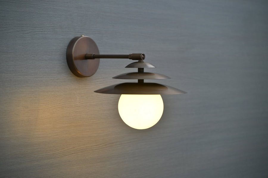 Front view of brass wall sconce with layered shades and globe diffuser, handmade modern lighting by Brass Leaf Studio