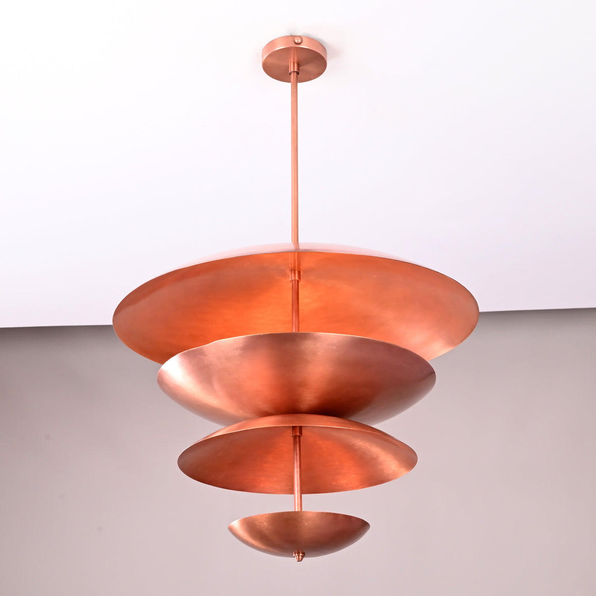 Bottom-angle view of the layered bowl-shaped brass chandelier showcasing its sculptural copper finish and floating disc design.