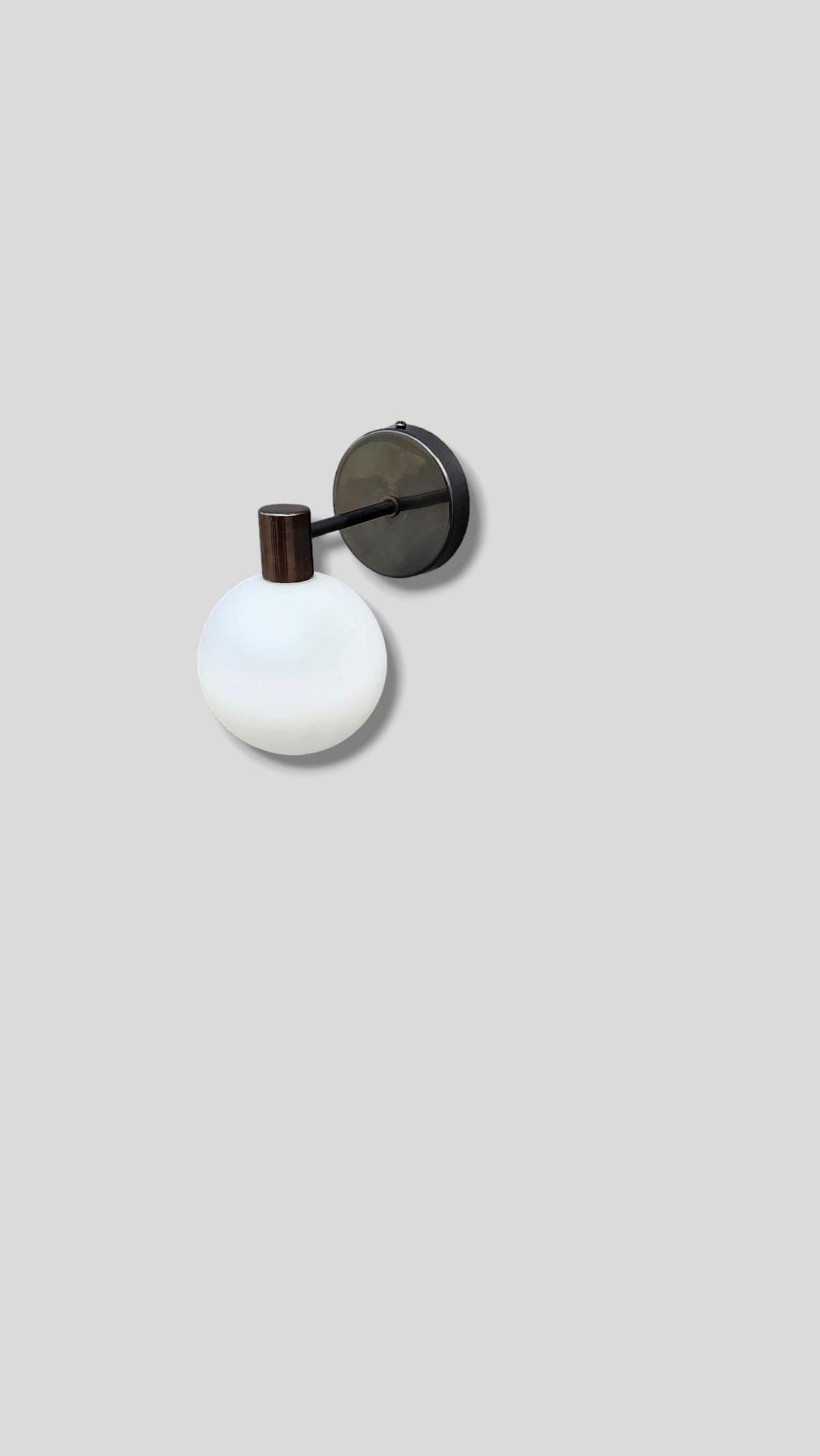 Angled view of industrial style brass wall sconce with opal glass light
