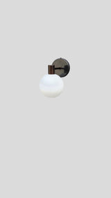 Front view of modern brass wall sconce with opal glass globe by Brass Leaf Studio