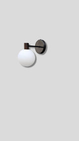 Side view of minimalist brass wall sconce with white glass globe shade