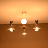 Warm glowing night view of a 9-light brass chandelier with cone shades and opal globes illuminating the ceiling.