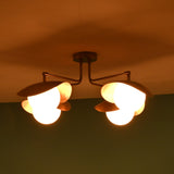 Side perspective of brass ceiling light at night highlighting curved bowl shades and warm illumination