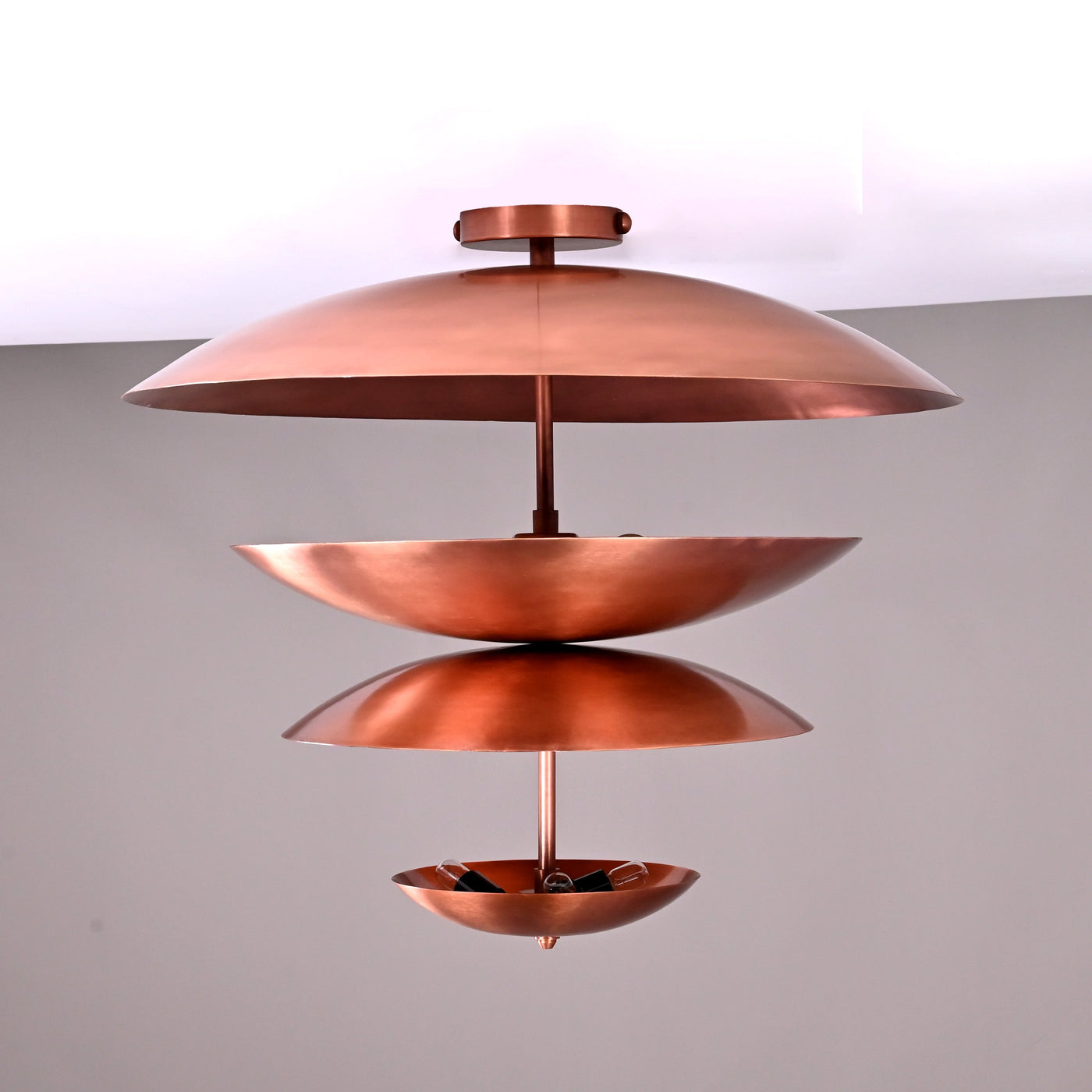 Front view of a 24x21 inch handmade multi-tier brass flushmount chandelier featuring sculpted bowl-shaped shades in a copper finish by Brass Leaf Studio.
