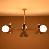 Night-time view of a mid-century brass chandelier with cone and globe lights casting a soft ambient glow.