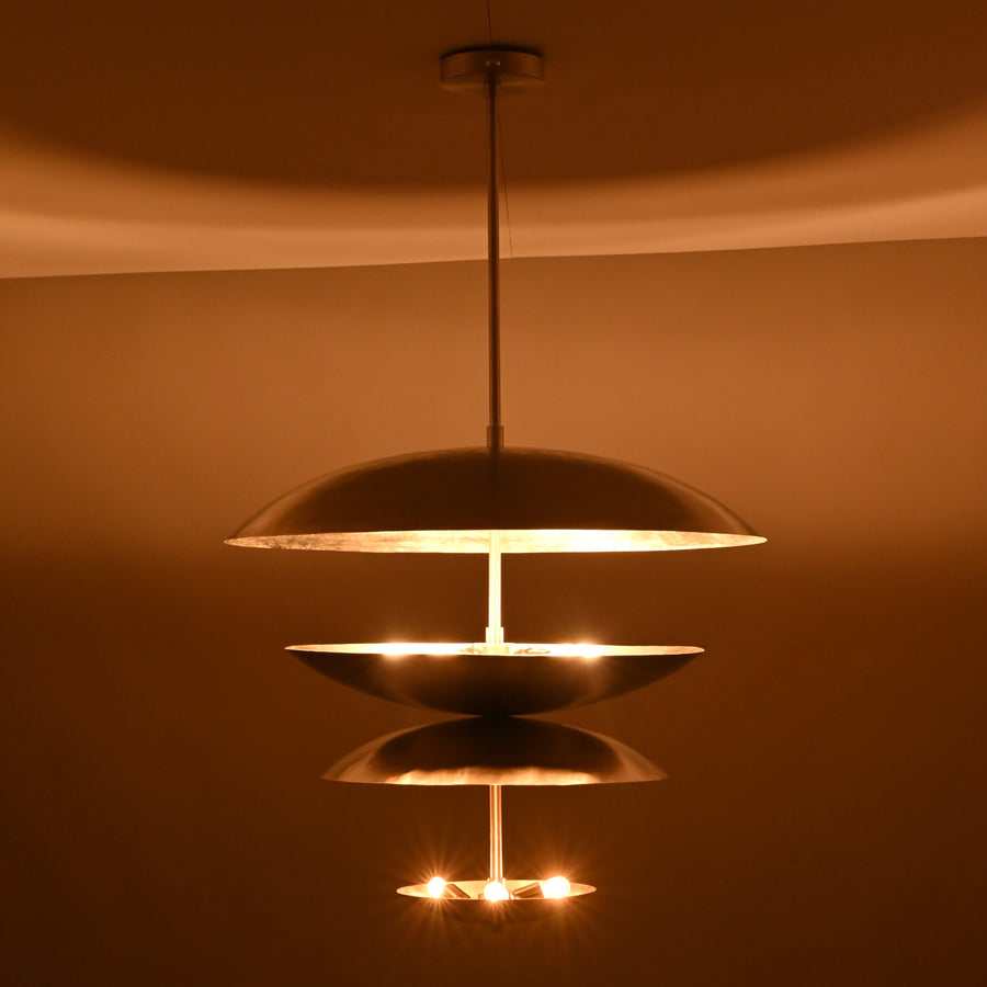 Modern multi-tier brass disc chandelier with sculptural floating bowls and soft uplighting by Brass Leaf Studio.