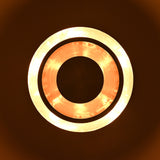 Glowing top view of a circular tiered disc light with bright illuminated rings and handcrafted metallic finish.