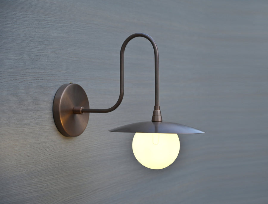 Handmade brass wall sconce with globe shade and curved arm design, industrial modern wall light for home interiors