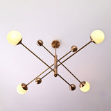 Top view of 4-light solid brass linear chandelier with opal glass globes in brushed brass finish.