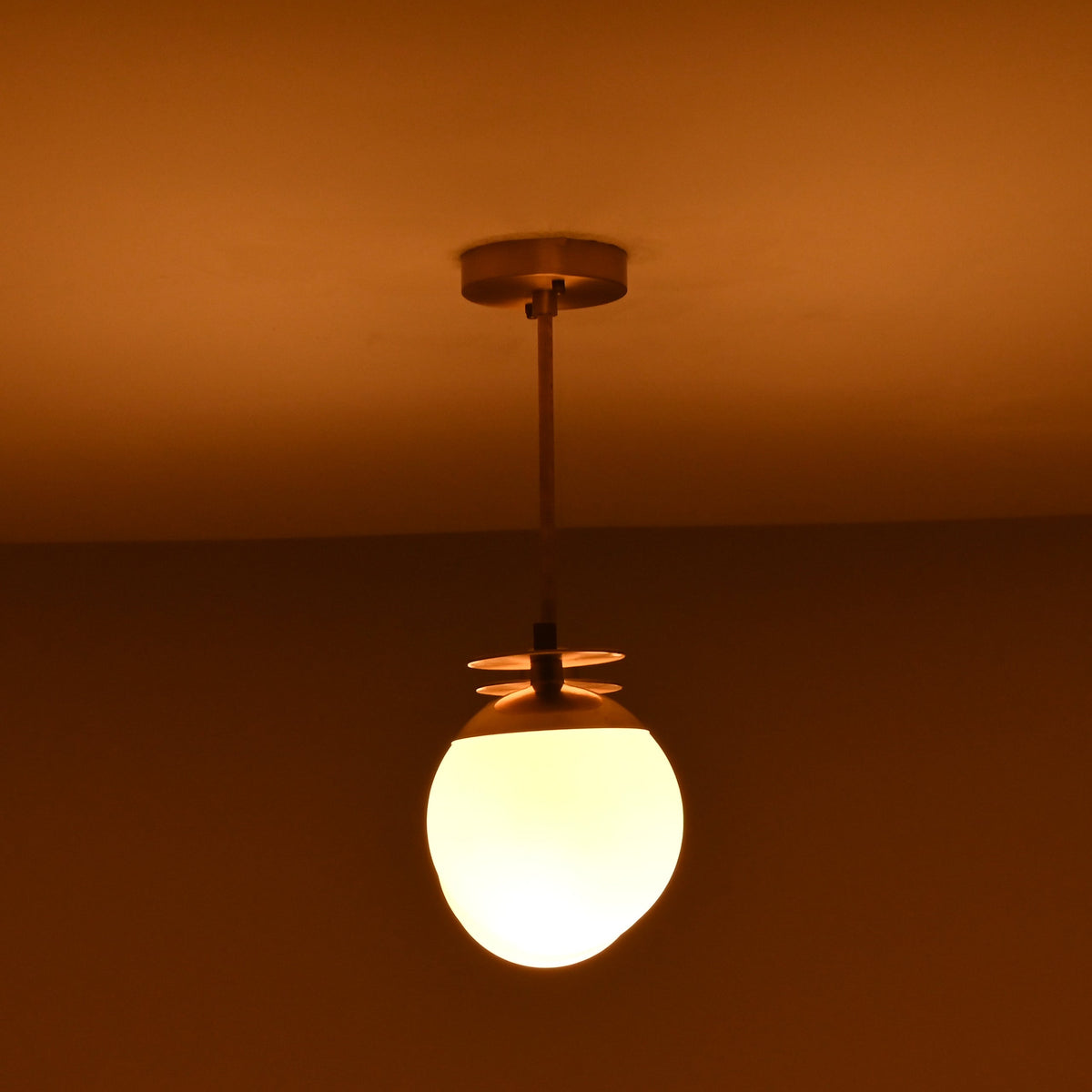 4 light brass linear chandelier illuminated in a dark setting, creating a warm and inviting ambient glow.