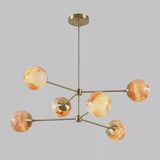 Front view of a modern brass chandelier with six marble glass globes, showcasing balanced proportions and minimalist industrial styling.