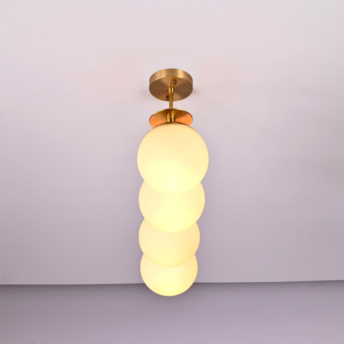 Vertical angle view of handcrafted brass chandelier featuring opal glass globes and brushed brass finish.