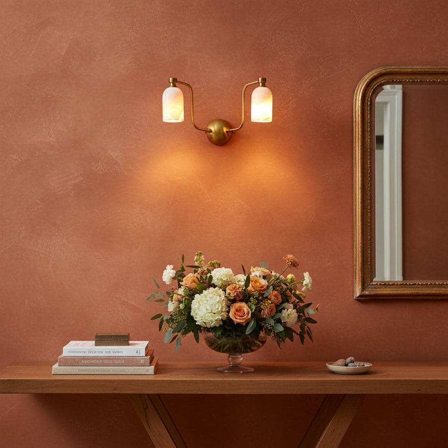 Dual alabaster cylinder wall light with curved brass arms and round brass patina canopy for elegant interiors