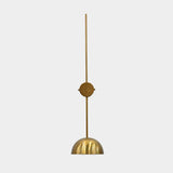 Brass patina bowl wall sconce closeup showing solid brass shade, slim wall stem, and warm interior glow