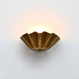 Brass patina ruffled wall light with sculptural fluted bowl shade creating soft ambient wall lighting