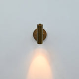 Side view of brass patina cylindrical wall sconce with adjustable-style support arm and round mounting plate