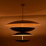 Evening glow of brass layered disc chandelier with multi-tiered bowl shades creating soft diffused light and dramatic ambience.