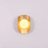 Brass shield globe sconce creating soft warm glow for luxury home and boutique interiors