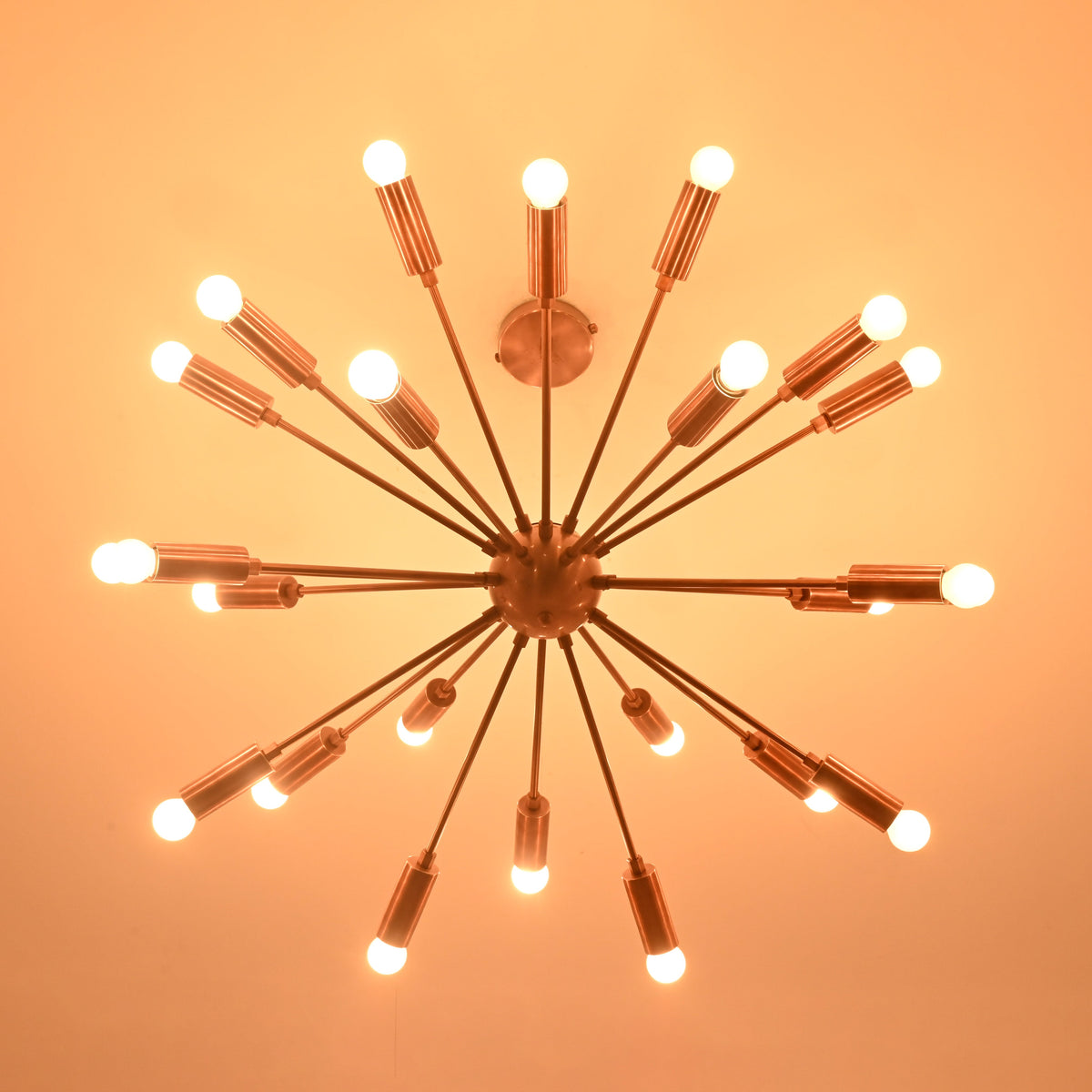 Bottom view of brass sputnik chandelier illuminated in dark setting with soft warm light.