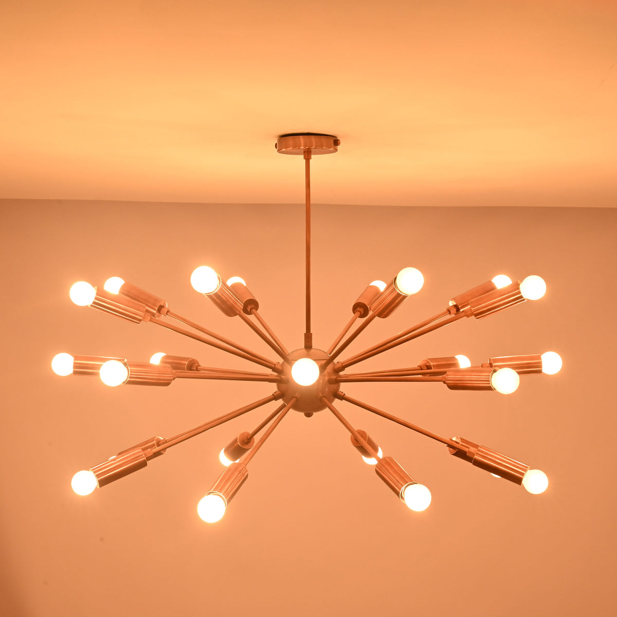 Brass sputnik chandelier glowing warmly in dark room creating dramatic ambient ceiling lighting.
