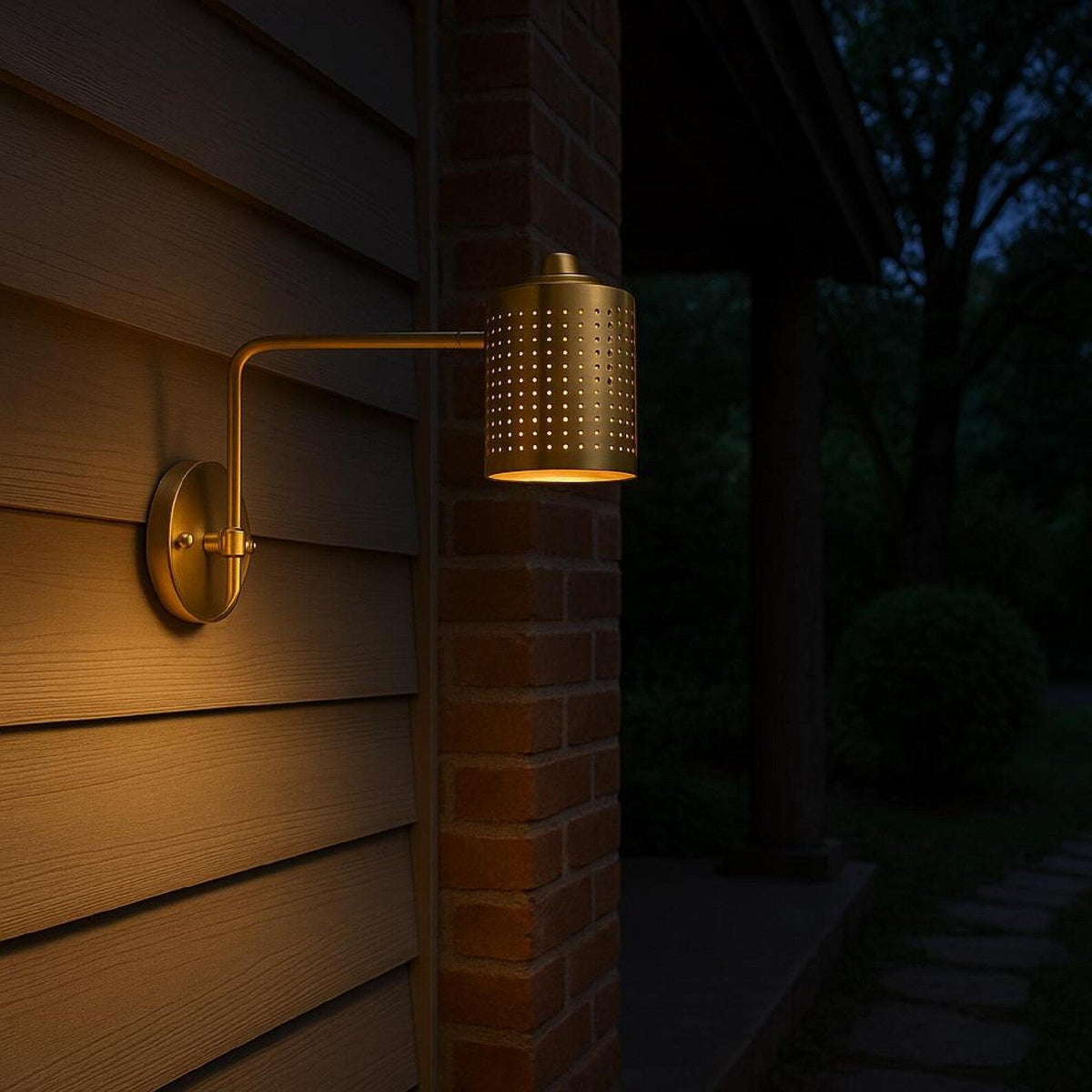 Brass swing arm wall sconce with perforated shade providing warm ambient lighting on exterior wall