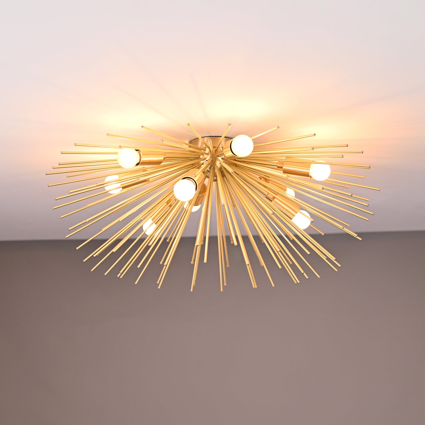 Brass urchin 9-light flushmount chandelier illuminated, showcasing radiant light spread and handcrafted brass rod design.