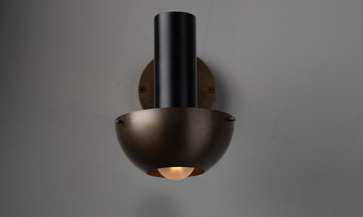 Front view of handcrafted brass wall light featuring a deep bowl shade and soft indirect glow for ambient interior lighting.