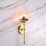 Polished brass wall sconce with teardrop glass shade mounted on white marble wall