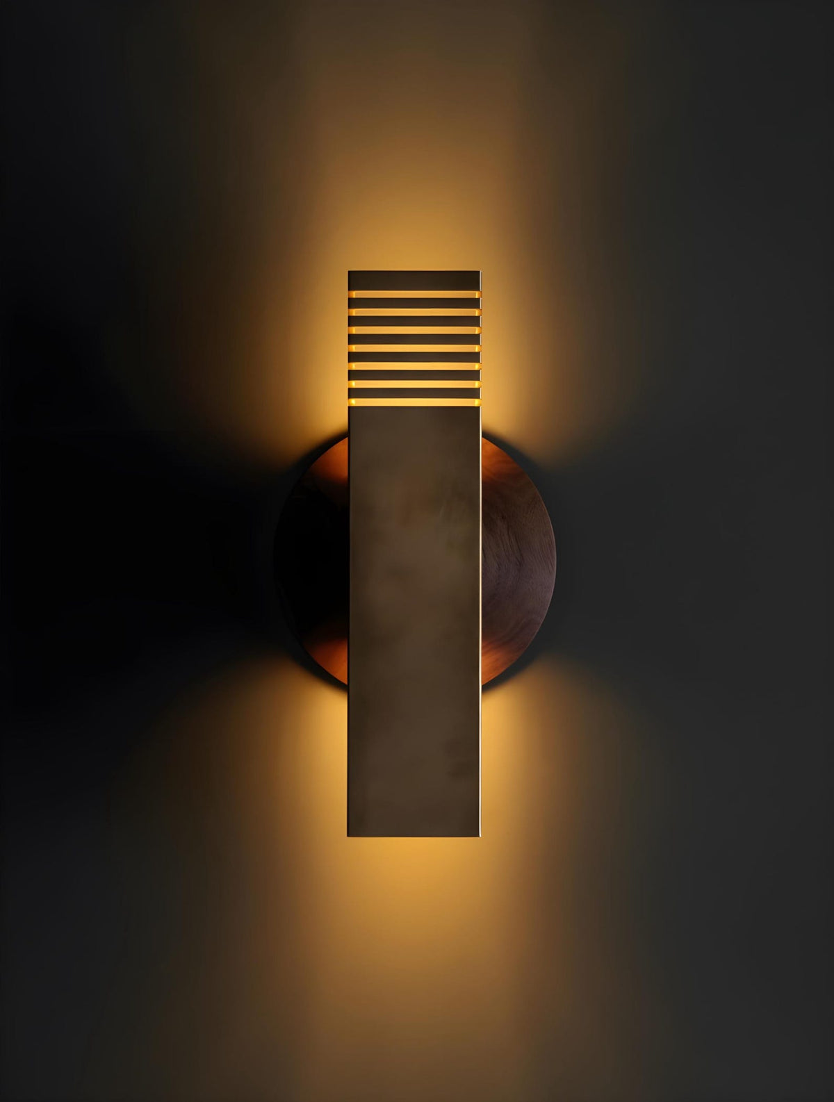 Modern brass wall sconce emitting warm ambient indirect lighting with soft glow on wall