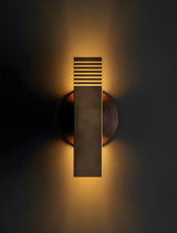 Modern brass wall sconce emitting warm ambient indirect lighting with soft glow on wall