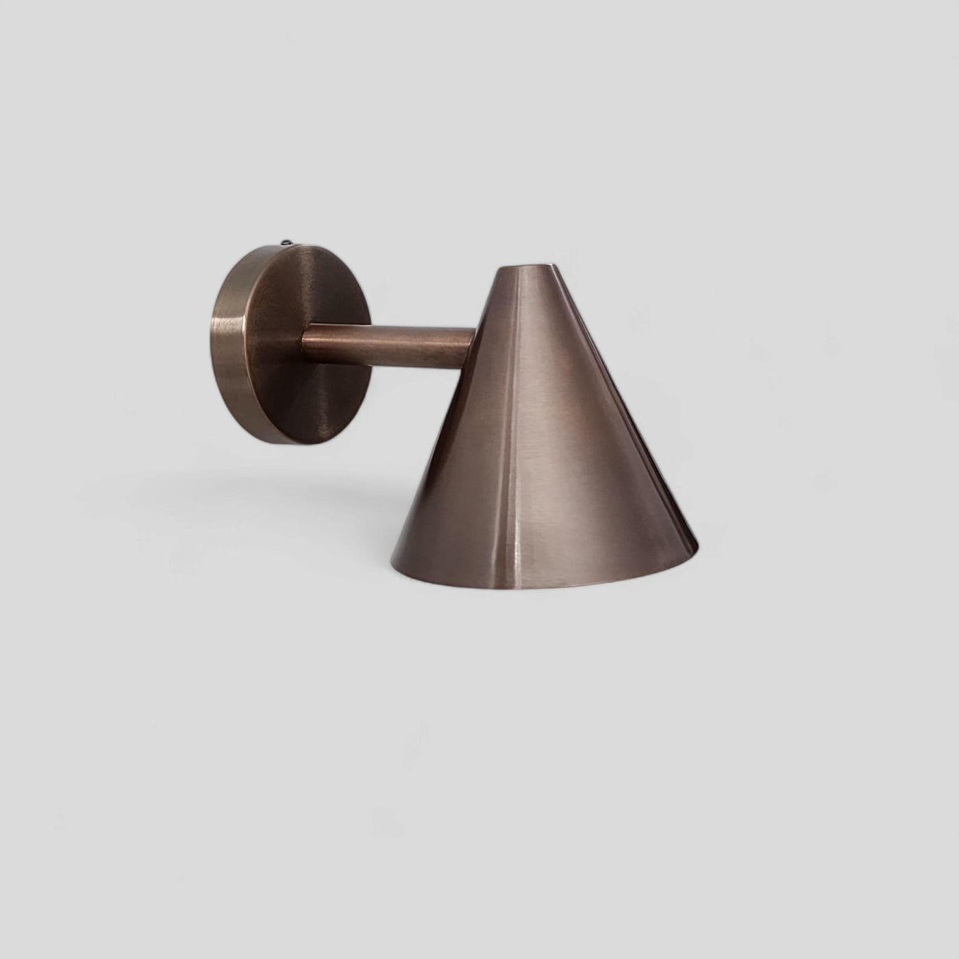Handcrafted brushed antique brass cone wall light with minimalist design and warm metallic finish by Brass Leaf Studio.