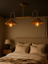 Modern brushed brass 2-light disc chandelier with scalloped bowl shades installed above a bedroom bed, providing warm ambient lighting