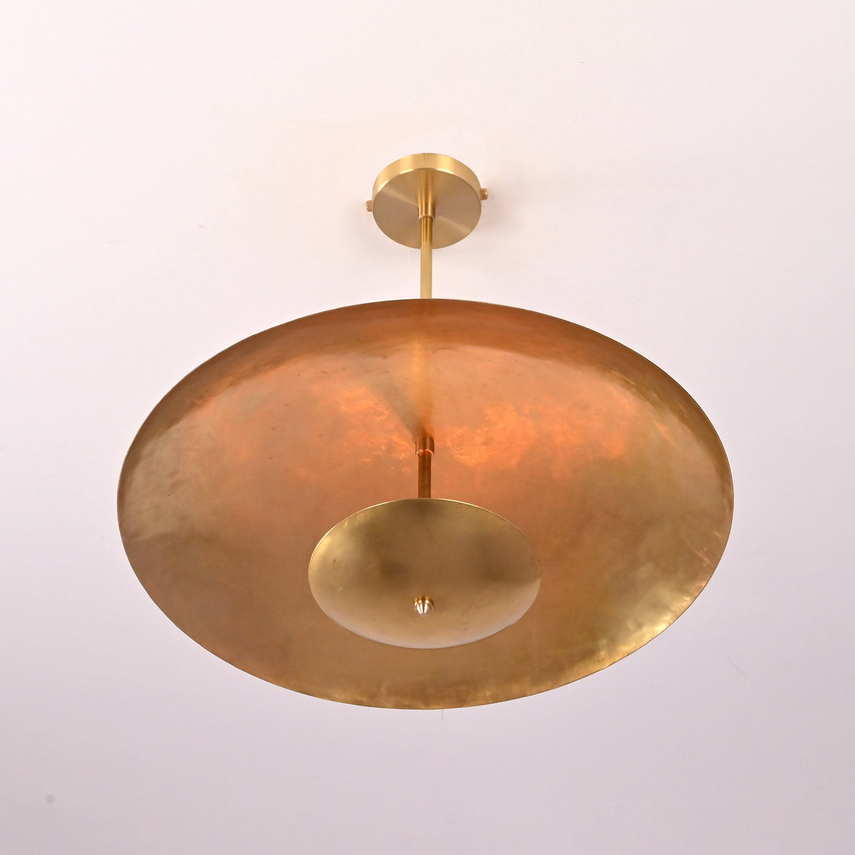 Bottom view of brushed brass bowl pendant highlighting circular disc form and solid brass construction.