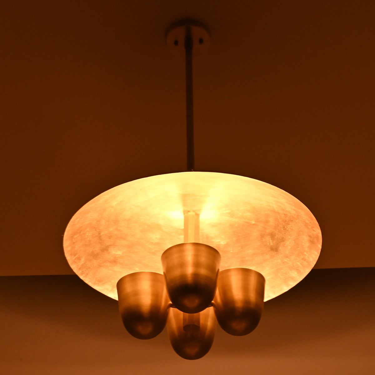 Handmade brass disc chandelier casting indirect ambient light, four bowl design ideal for dining rooms and living spaces