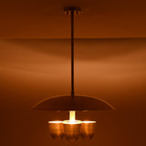 Brushed brass disc chandelier with four bowl shades illuminated, creating warm ambient indirect lighting in modern interiors