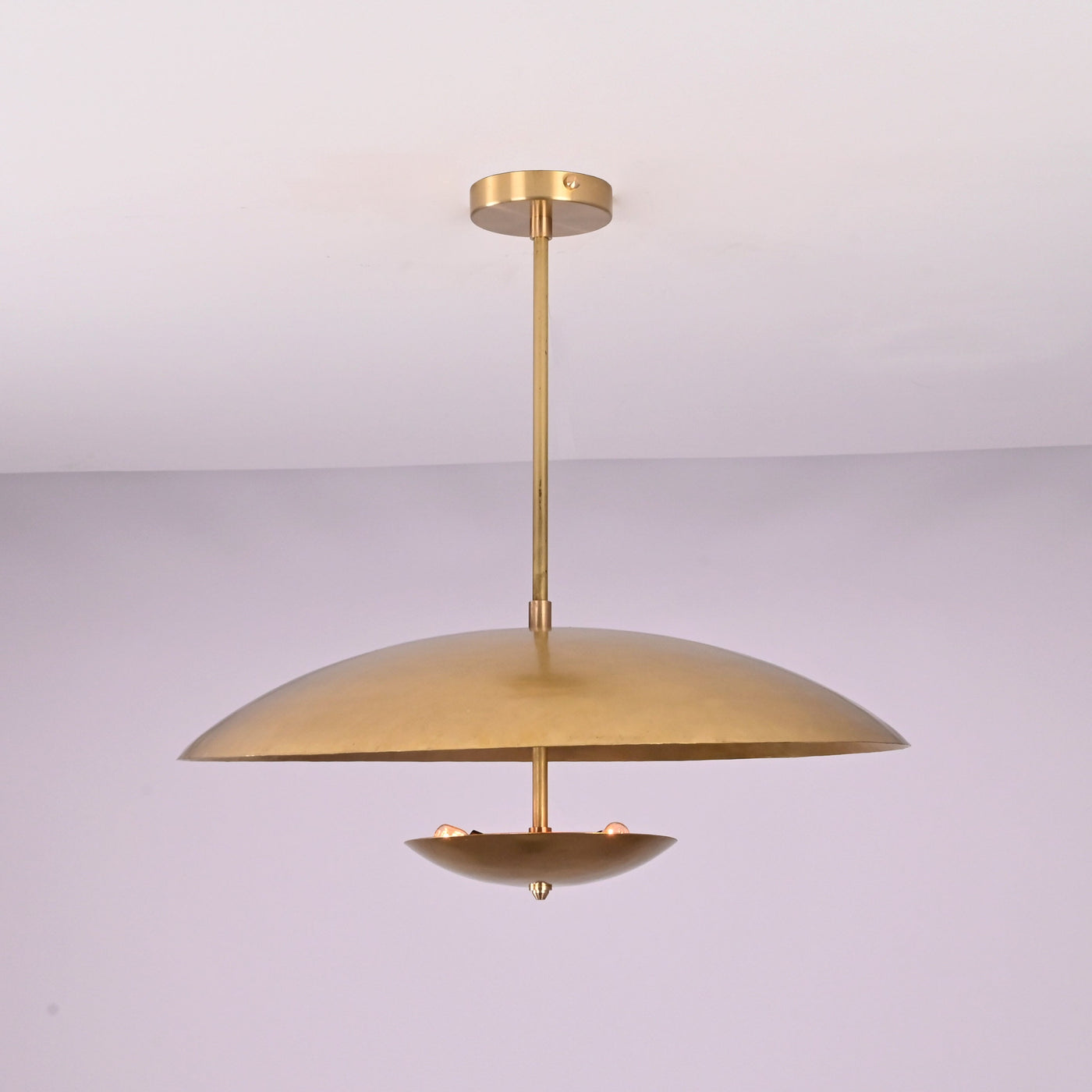 Front view of brushed brass disc pendant light with layered bowl shades and minimalist profile.
