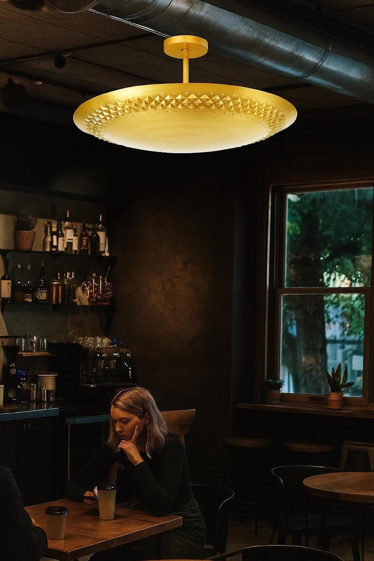 Brushed brass flush mount ceiling light illuminating a contemporary café seating area