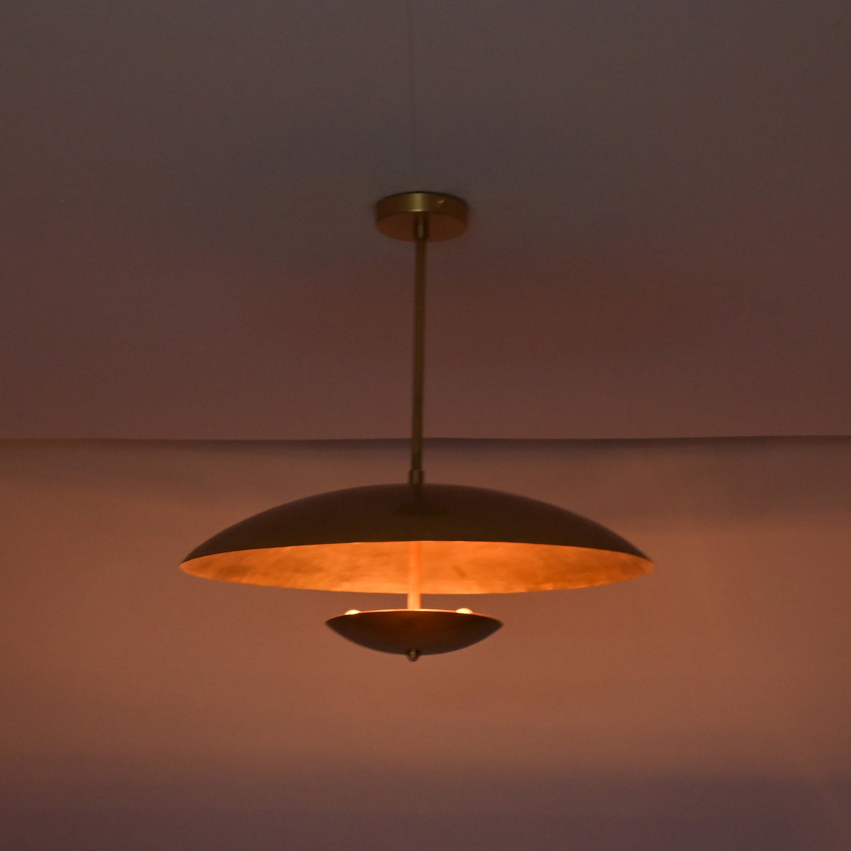 Detail view of brushed brass pendant ceiling canopy and solid brass drop rod connection.
