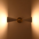 Brushed brass wall light closeup showing central sphere, arm detail, and white enamel cone shades