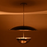 Chrome bowl-and-disc pendant light producing warm indirect illumination from below