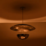 Chrome brass disc chandelier illuminated at night with warm ambient lighting and soft reflections