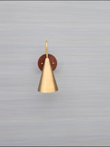 Mounted view of cone brass and wood wall light on neutral background showing refined craftsmanship and smooth brass patina.