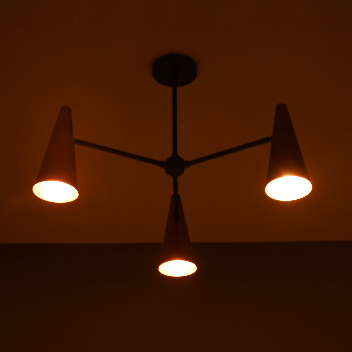 Close-up of glowing copper cone shade highlighting warm light diffusion and brass craftsmanship