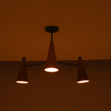 Three light copper cone chandelier in dark setting creating moody, atmospheric ceiling lighting